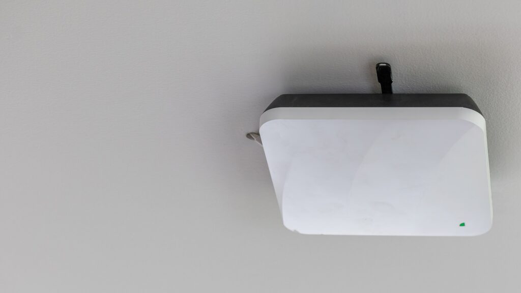 A small wireless access point mounted on a wall near a kitchen doorway
