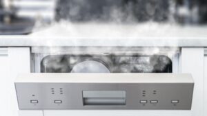 A built-in dishwasher with its door released a few inches and steam rising from the gap
